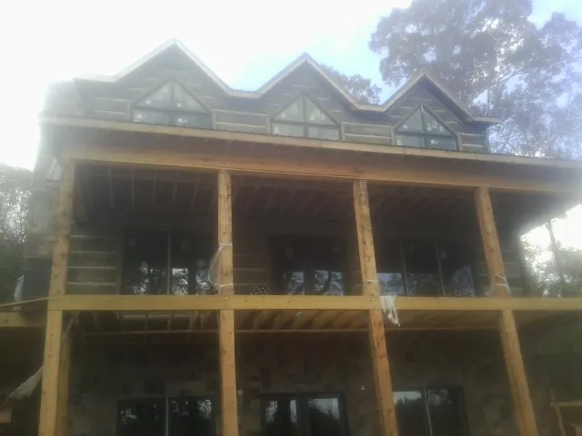 Dormers and porch framing on a large log home under construction — Roof Coating work by our crew in Garrison