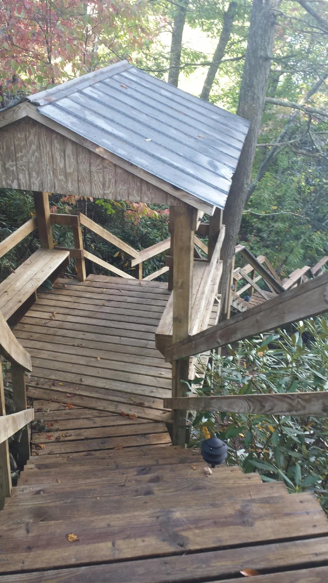 Metal roofed shelter over wooden steps on a wooded walkway — Skylight Repair & Installation work by our crew in Garrison